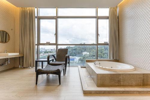a bathroom with a tub and a chair and a large window at Allee Hotel in Yongin