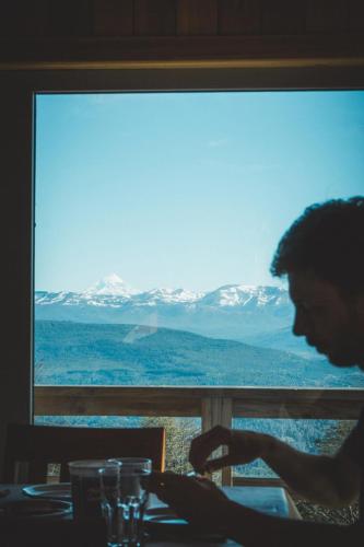 a man sitting at a table in front of a window at Bosque Nevado in San Martín de los Andes