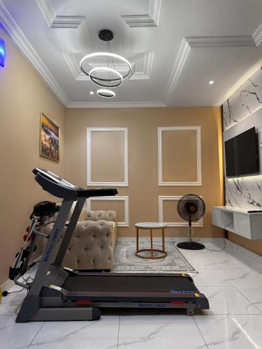 a living room with a treadmill and a room with a tv at Near Lakowe Golf and Lekki FTZ Minutes From Awoyaya with Constant Power, Wi-Fi, Gym by Crystal Stays in Eleputu