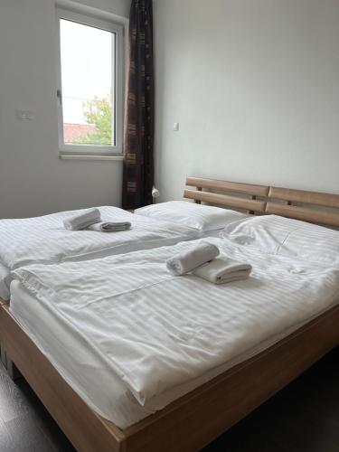 a large white bed with two towels on it at Fine Restaurant & Apartments in Malacky