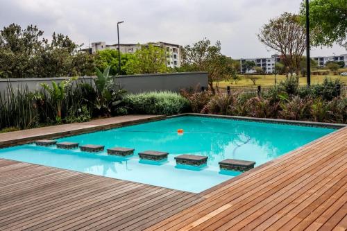 a swimming pool with a wooden deck and a swimming poolvisor at The Cozy Maldives in Durban