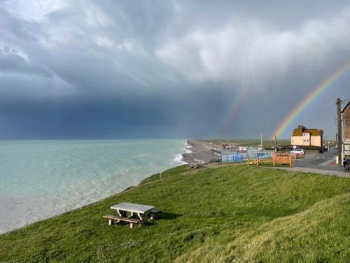a rainbow over the ocean with a picnic table on a hill at Le 104, vue mer in Ault