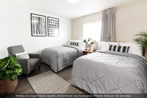 a bedroom with two beds and a chair at InTown Suites Extended Stay Austin TX - North Lamar in Austin