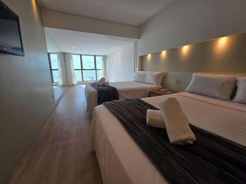 Una habitación de hotel con dos camas y un televisor. en Beach Class Executive por Yolo, en Recife