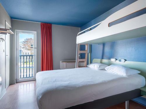 a bedroom with a white bed with a blue wall at ibis budget Caen Hérouville in Hérouville-Saint-Clair
