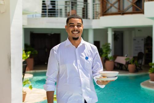 a man in a white shirt holding a bowl at ZAN Tropical Island in Bwejuu
