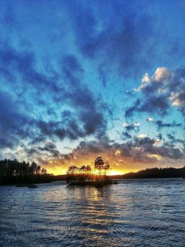 a island in the middle of a lake with a sunset at Stuga Ani in Svartå
