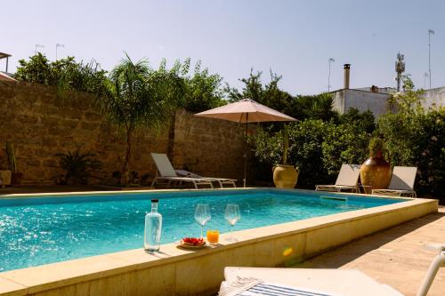 a swimming pool with wine glasses and an umbrella at B&B Don Alessandro in Surbo