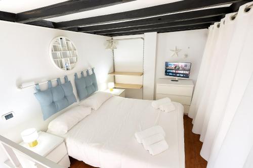 a white bedroom with a white bed and a television at Trastevere Stars in Rome