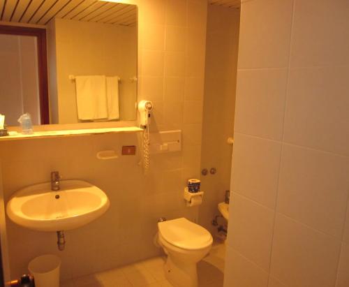 uma casa de banho com um lavatório, um WC e um espelho. em Hotel Villaggio Calaghena em Montepaone