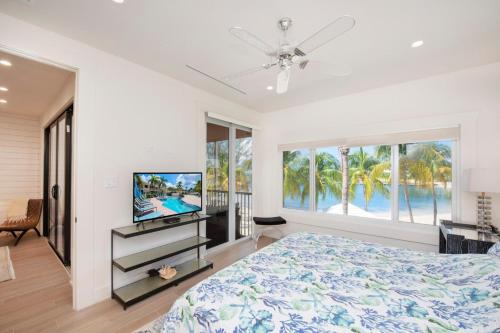 - une chambre avec un grand lit et une télévision dans l'établissement Starfish Kai - Serene Beachfront Condo with Stunning Bay Views & Resort Amenities, à Driftwood Village