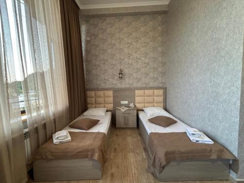 a room with two beds and a table in it at TIGRAN Hotel by Black & Gold in Goris