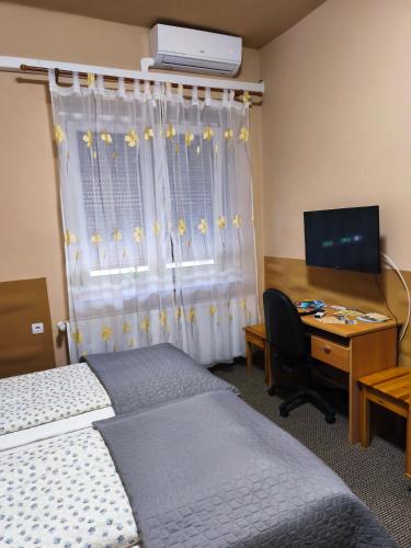 a room with two beds and a desk with a computer at Vár-Liget Vendégház in Kisnána