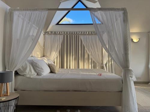 a bedroom with a canopy bed with a window at Sunset View in Rivière Noire