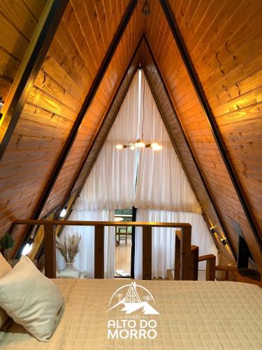 a bed in a room with a wooden ceiling at Chales alto do morro 1, conforto e vista privilegiada in Rancho Queimado