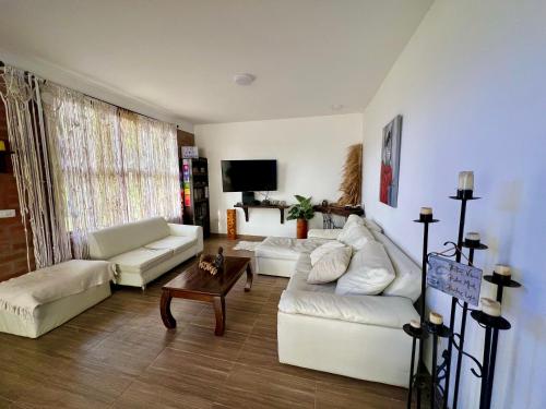 a living room with white couches and a tv at Villa Daniela Restrepo in Restrepo