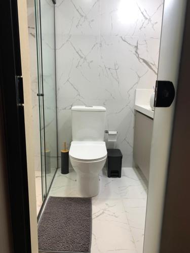 a bathroom with a toilet and a glass shower at Chales alto do morro 1, conforto e vista privilegiada in Rancho Queimado