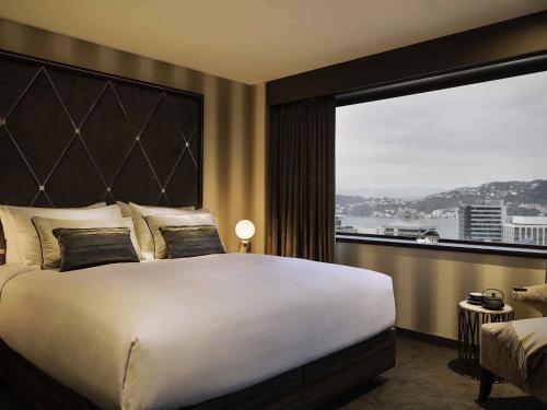a bedroom with a large bed and a large window at Sofitel Wellington in Wellington