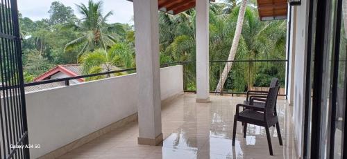 a balcony with two chairs and a table and trees at The Coconut tree villa in Dharga Town