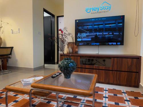 a living room with a tv and a vase on a coffee table at Amber Cove Impression City By Heystay Management in Melaka
