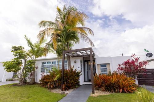 a white house with a palm tree in front of it at Signature's Dorado Relaxing Villa in Dorado