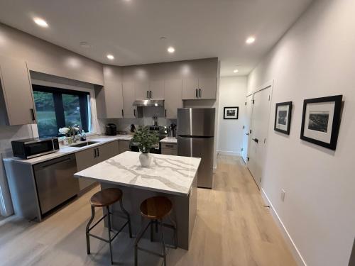 cocina con encimera y 2 taburetes en Modern 2BR Coach House, West Van- New Construction, en West Vancouver