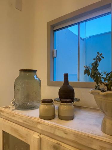 three vases sitting on a table next to a window at Pousada Estrela do Norte in Pipa