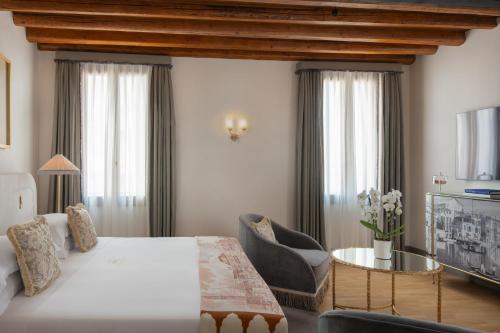 a bedroom with a large white bed and a table at Hotel Gabrielli Venezia - Starhotels Collezione in Venice