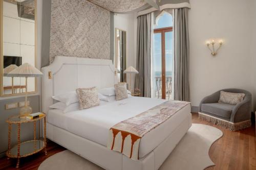 a bedroom with a large white bed and a chair at Hotel Gabrielli Venezia - Starhotels Collezione in Venice