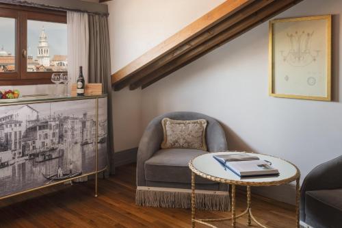 a living room with a chair and a table at Hotel Gabrielli Venezia - Starhotels Collezione in Venice