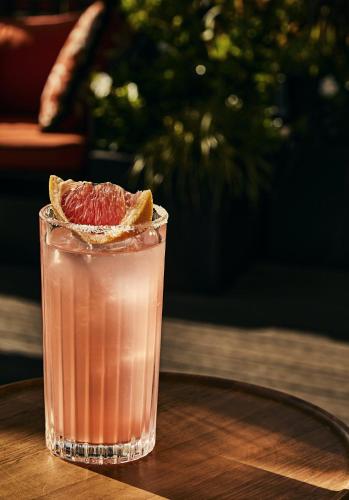 a drink with a grapefruit slice on a wooden table at Hotel Gabrielli Venezia - Starhotels Collezione in Venice