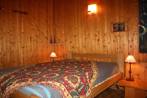 um quarto com uma cama com paredes de madeira e 2 candeeiros em Les Myosotis em Arêches