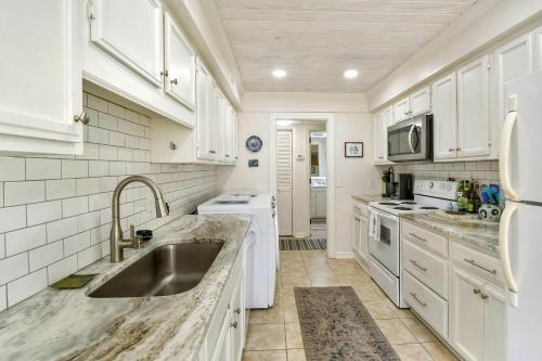 a kitchen with white cabinets and a sink at Stepless in St. Simons in Ebo Landing