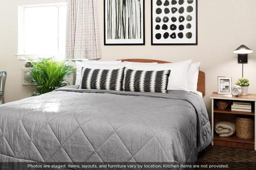 a bedroom with a bed with a gray comforter at InTown Suites Extended Stay Atlanta GA - Lithia Springs in Lithia Springs