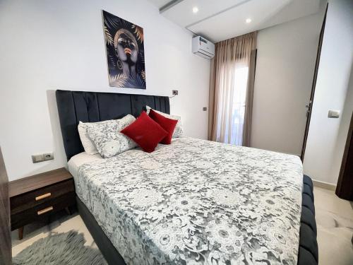 a bedroom with a large bed with red pillows at Centre-ville - bien équipé - Neuf - WiFi - Calme in Kenitra