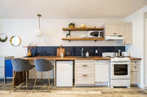 una cucina con mobili bianchi e un bancone con sgabelli di Studio Vintage by Gestion ELITE a Mont-Tremblant