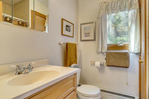 a bathroom with a sink and a toilet and a window at Riverfront Home with Hot Tub Near Killington Resort in West Bridgewater
