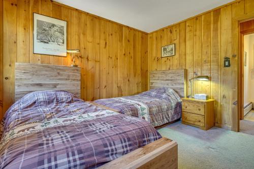 two beds in a room with wood paneled walls at Riverfront Home with Hot Tub Near Killington Resort in West Bridgewater