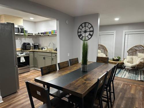 a dining room table with chairs and a clock on the wall at Unique 3Bd 2Ba GAME ROOM mins to Downtown in Winston-Salem