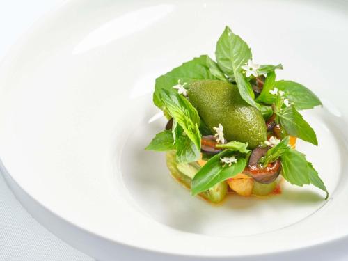 a plate of food with avocados and greens on it at Hotel Des Arts Saigon Mgallery Collection in Ho Chi Minh City