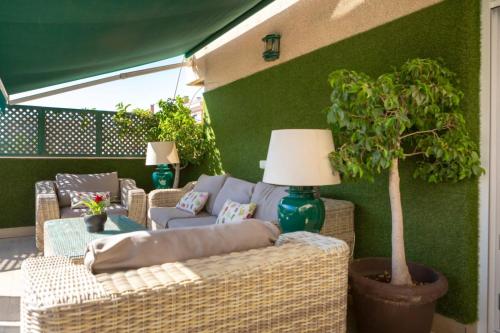 a patio with wicker furniture and a potted tree at AMAZING ROOFTOP, 70 M TERRACE,Pool,BEACH,PARKING in Málaga