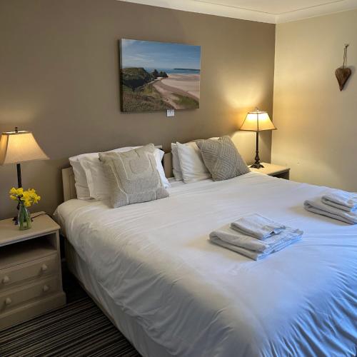 a bedroom with a large white bed with towels on it at The Gower Golf Club B&B in Gowerton