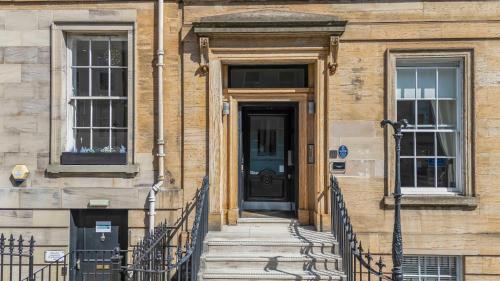 a building with a black door and stairs in front at Cairn BNB Introduces Blythswood Apartments - Experience exceptional luxury living in Glasgow's most desirable location in Glasgow