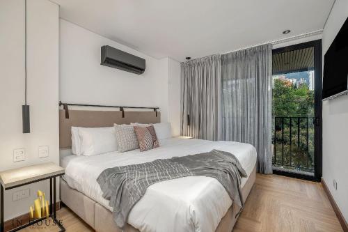 ein Schlafzimmer mit großem Bett und Fenster in der Unterkunft Morph 401 - Modern apt High Ceilings BBQ/Jacuzzi in El Poblado