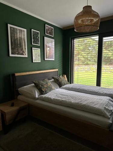 a bedroom with a bed with green walls and a window at FORESTHOUSE in Łubowo