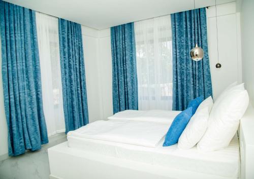 een wit bed met blauwe gordijnen in een kamer bij Smile Apartments Arusha in Arusha