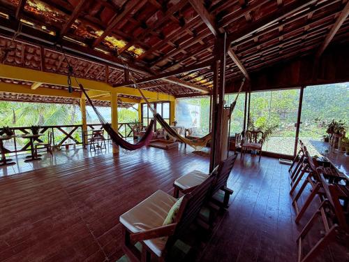 een grote kamer met een hangmat en tafels en stoelen bij Pousada Praia do Amor Pipa in Pipa