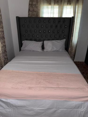 a bedroom with a large bed with a black headboard at Raine house in Ukunda