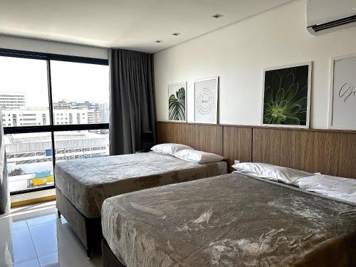 a hotel room with two beds and a window at Edifício SKY Acomodações in Maceió