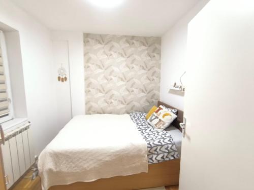 a small bedroom with a white bed and a wall at ANKA apartman in Smederevo